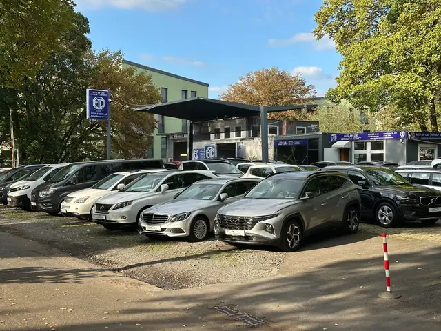Einfahrt zum Hof von EYC Global in Köln-Ostheim mit Firmenschild und Gebrauchtwagen